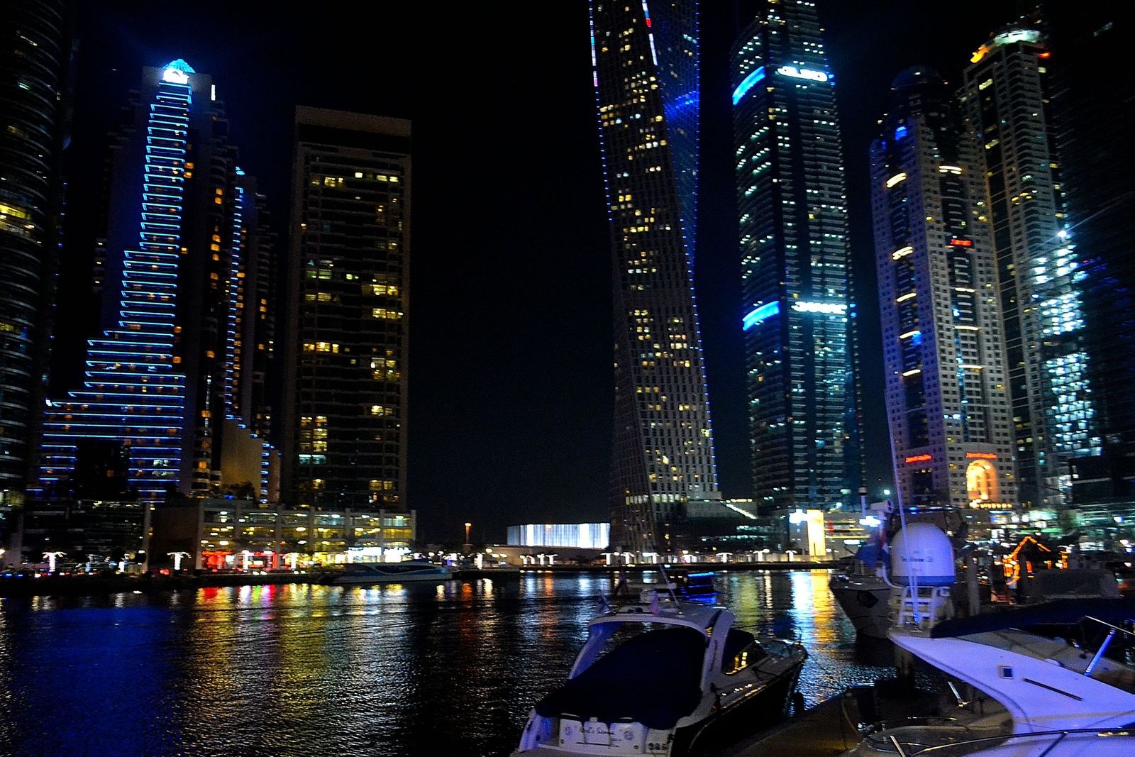 Dubai Marina towers lit up at night with yachts moored in the marina