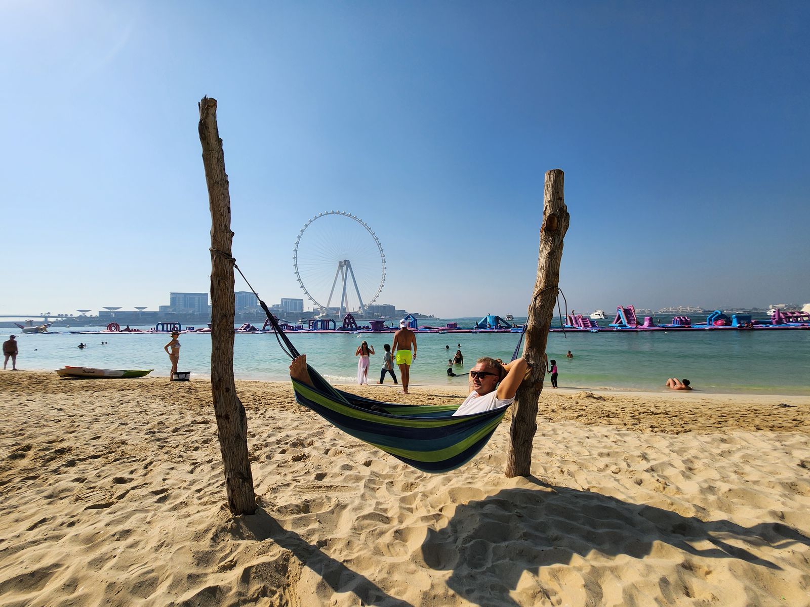 A hammock on JBR beach with Ain Dubai and swimmers in the distance