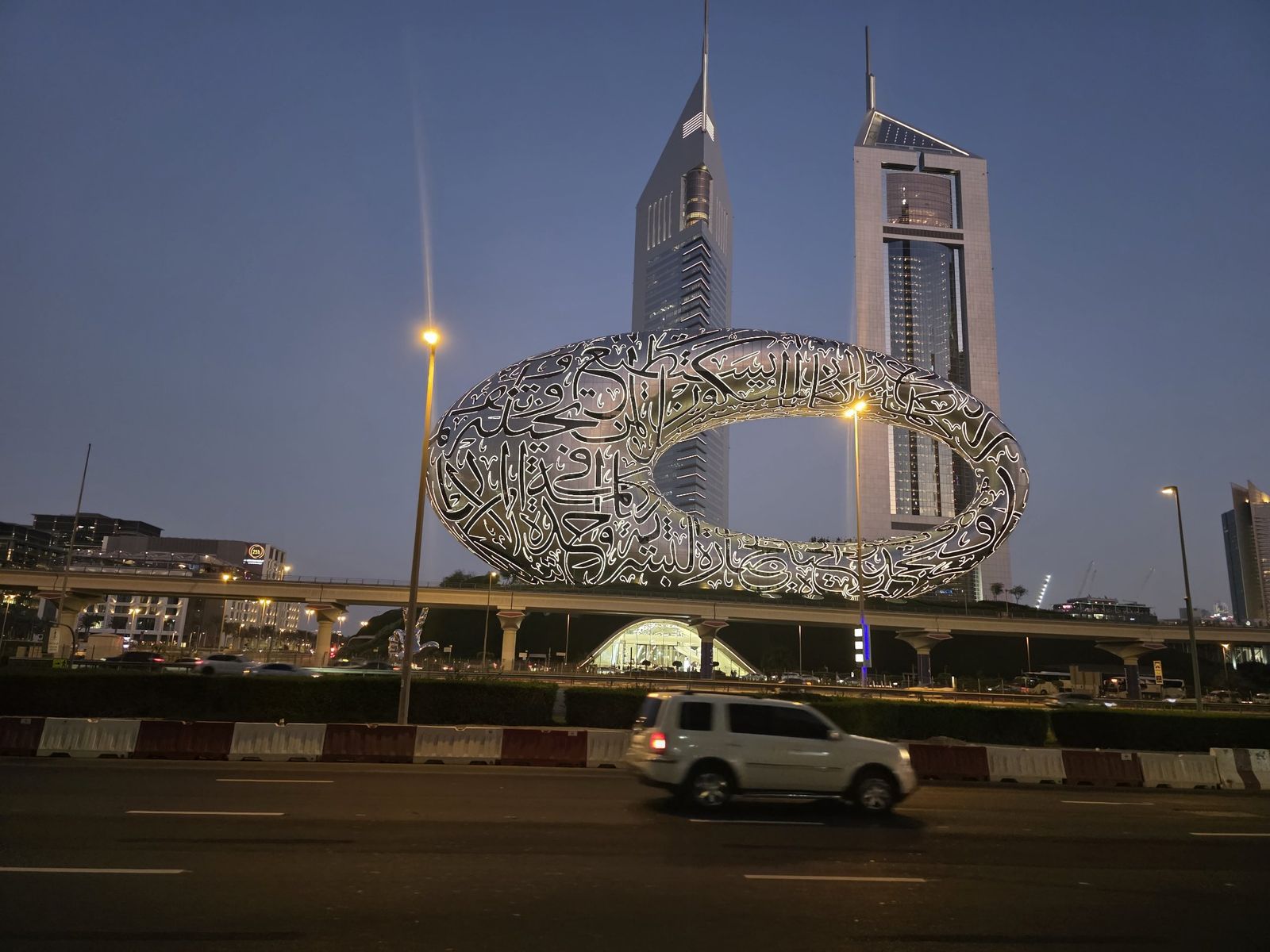 The Museum of the Future's calligraphy-covered torus lit up at dusk, seen from across Sheikh Zayed Road